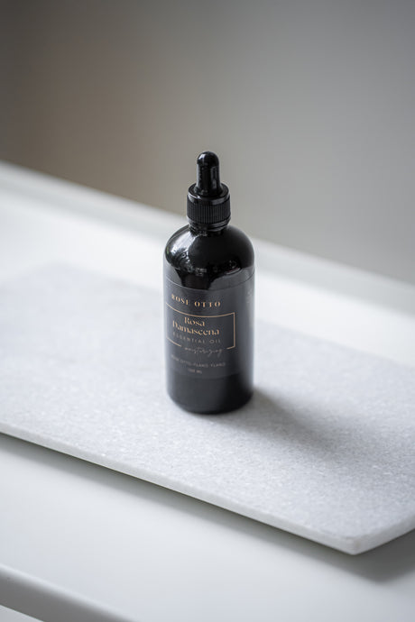 Black bottle with dropper labeled 'Fused Fragrance' on a white surface