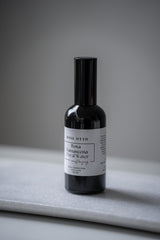 Bottle of Rosa Otto floral water on a gray surface with a neutral background