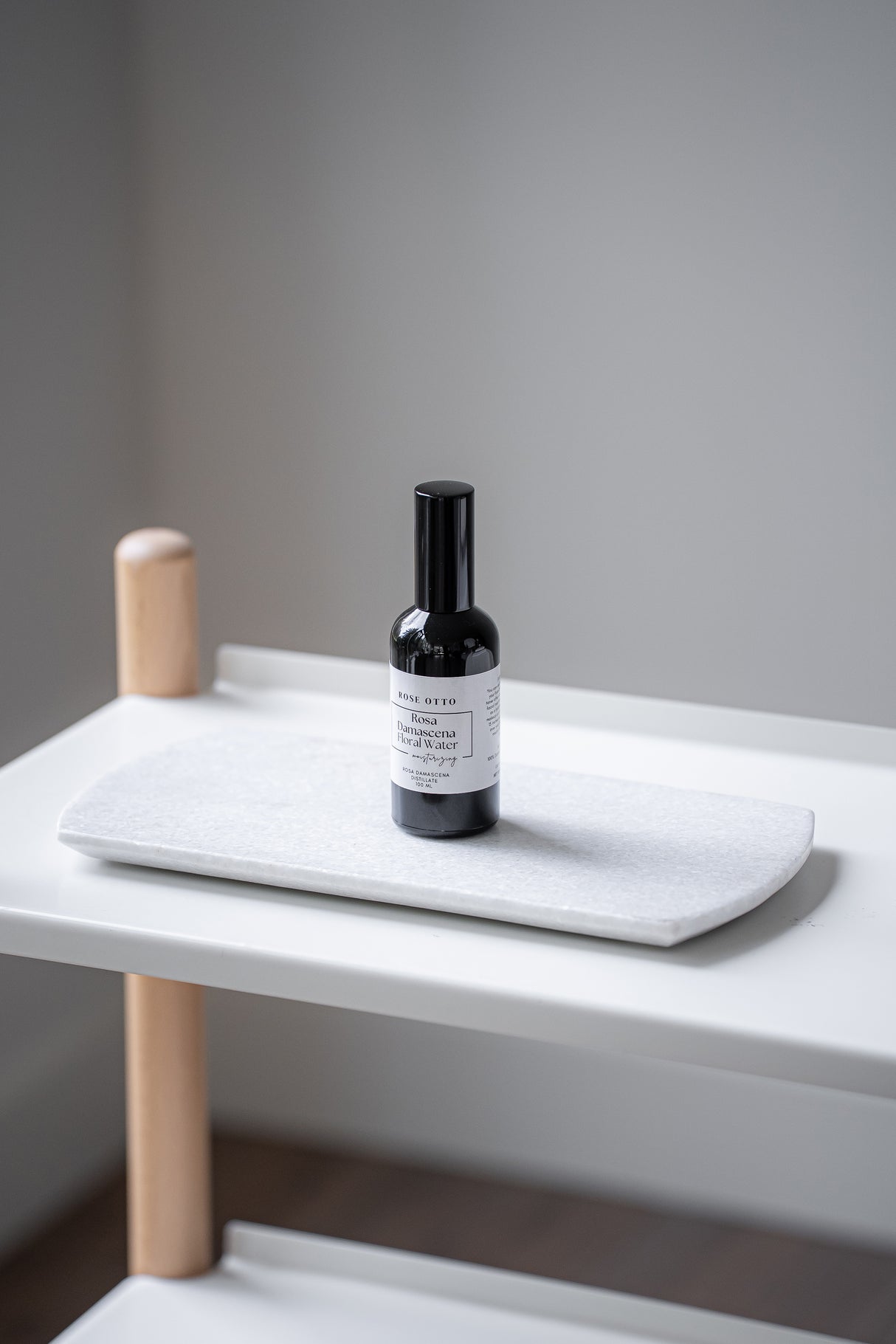 Small bottle with label on a white surface against a gray wall