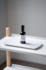 Small bottle with label on a white surface against a gray wall